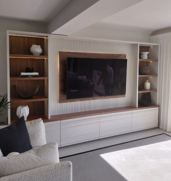 Contemporary media wall with white fluted panels, walnut accents and integrated LED shelf lighting
