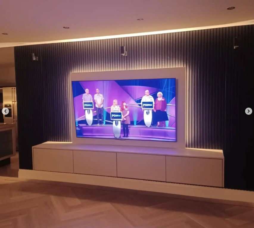 Contemporary media wall with dark slatted panels and LED lighting